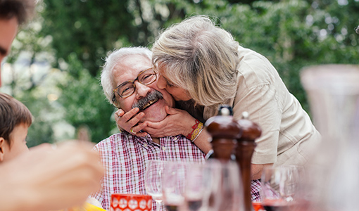 Senior woman kissing husband on cheek at picnic table