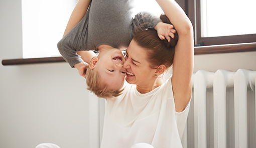 Happy young mother with little son on bedroom home background