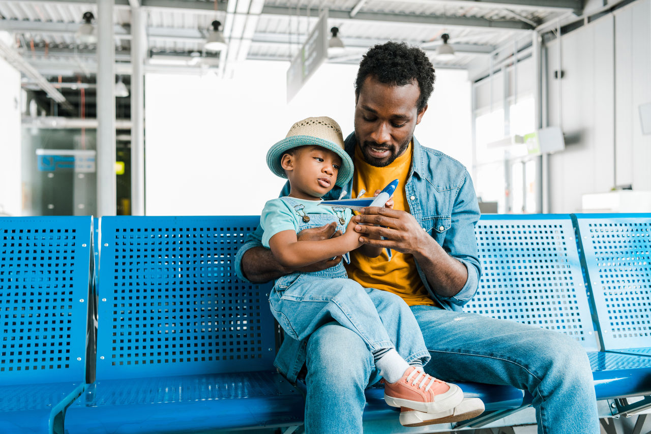 African american father and son playing with toy plane in departure lounge stock photo