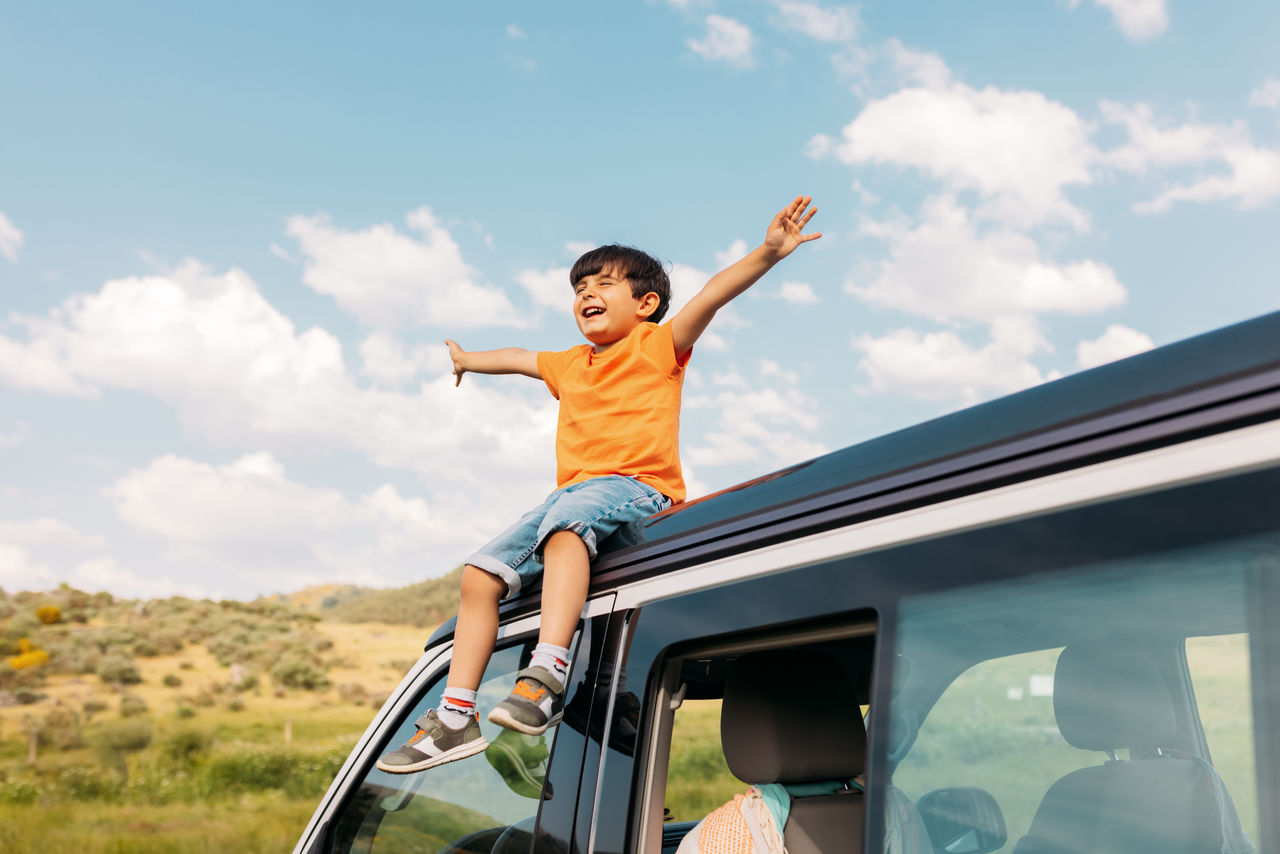 Happy Kid With Outstretched Arms Resting On Transport Roof